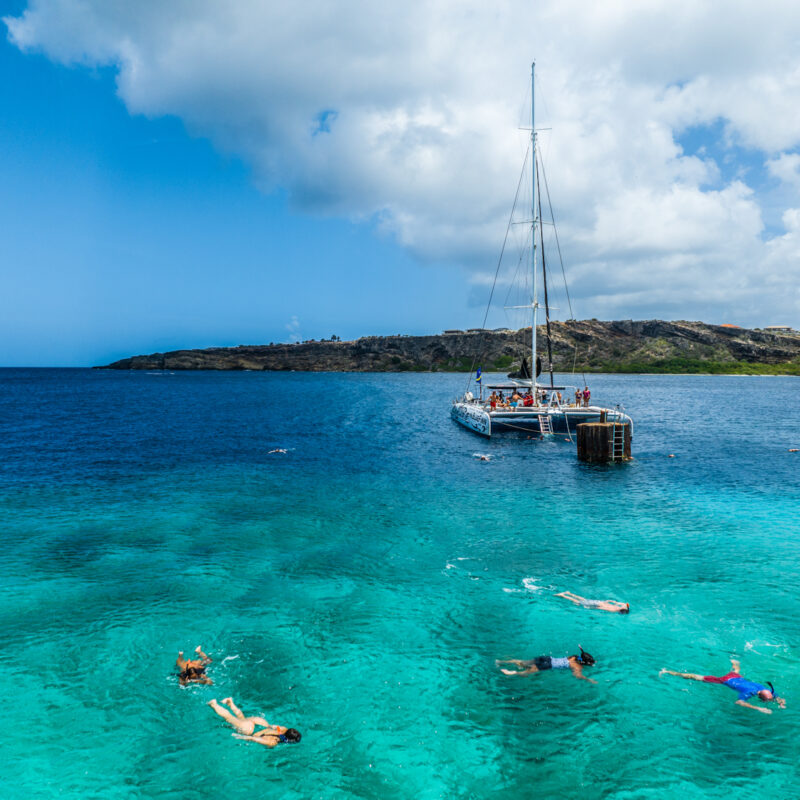 Catamaran in sea with people snorkeling